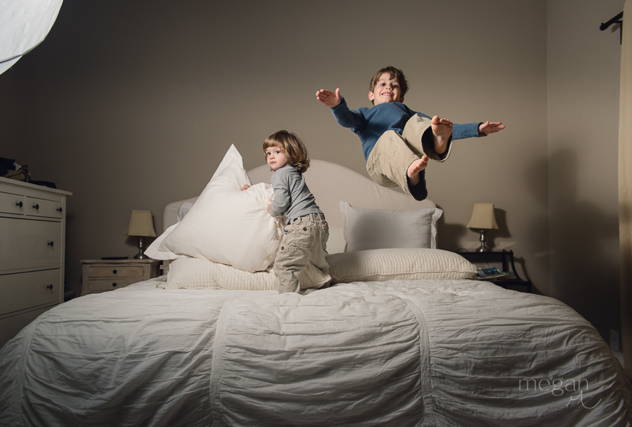 young boys play on bed lit with off camera flash