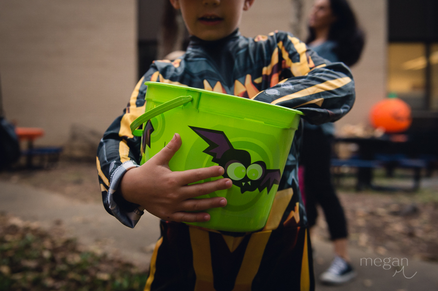 Child dressed up for halloween holds a candy bucket