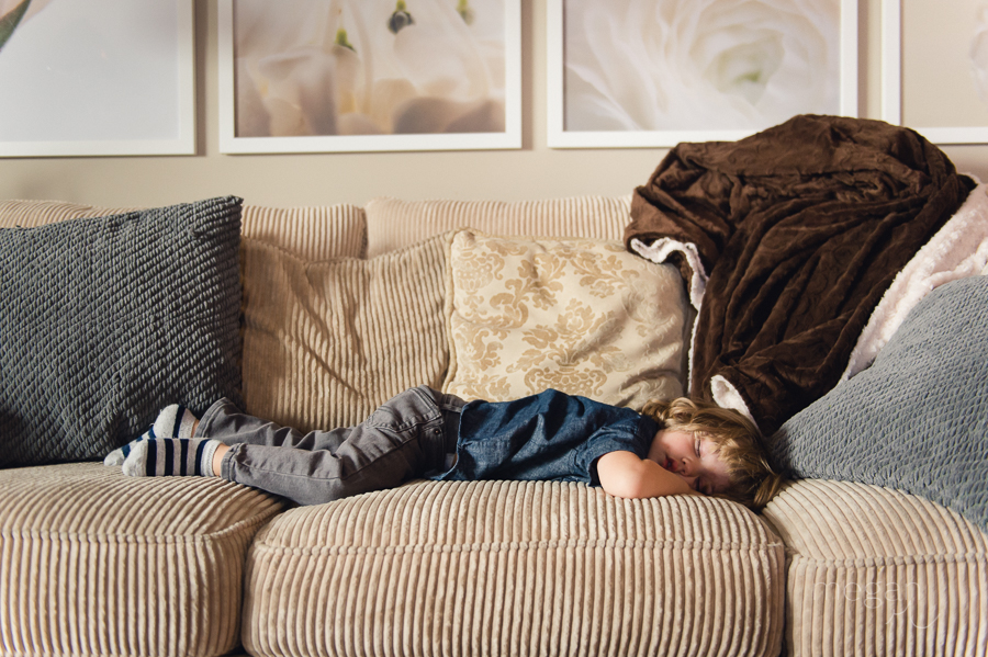 Toddler boys naps on the couch in natural light
