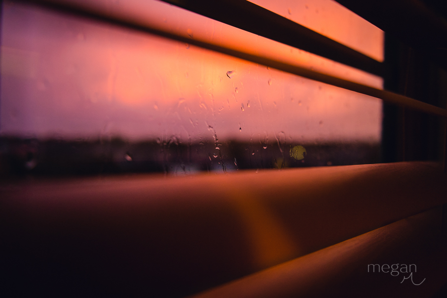Colorful sunset viewed from inside of a home through shades