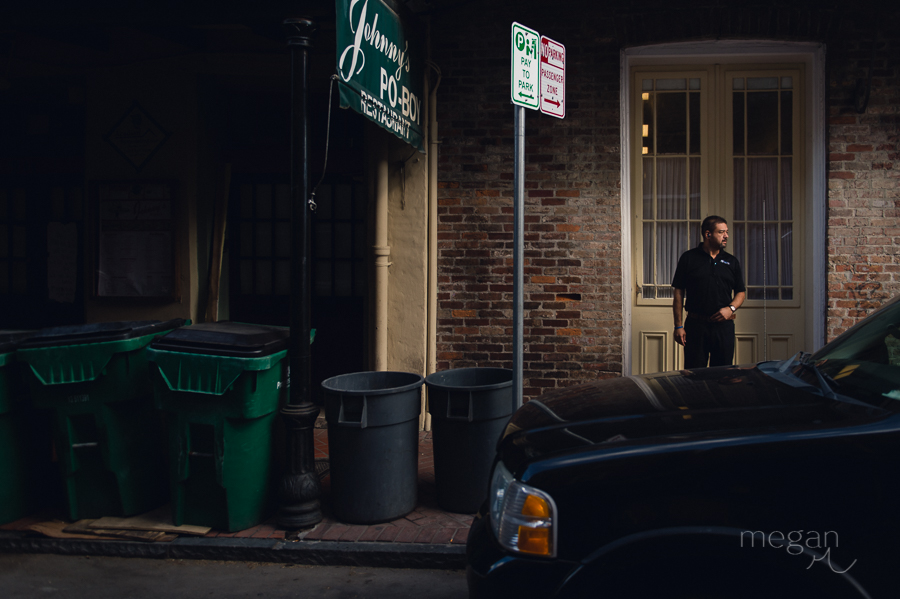 man stands amongst garbage bins in the morning in the french quarter of new orleans