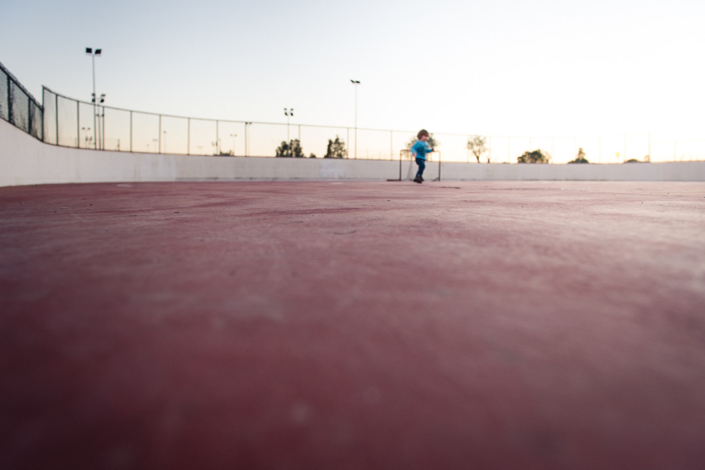 young child runs on hockey rink at sunset by Megan Cieloha