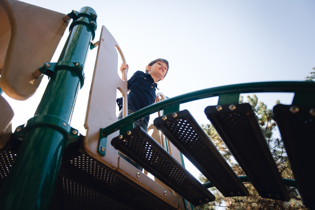 Photo of child at the top of a ladder on a playground by megan cieloha